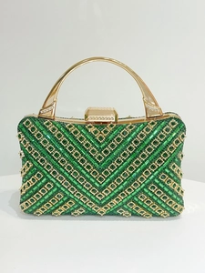 Dettaglio della pochette da sera verde con strass, manico dorato e motivo a V in cristallo