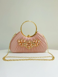 Close-up of pink pleated satin evening bag with crystal floral motif and gold handle