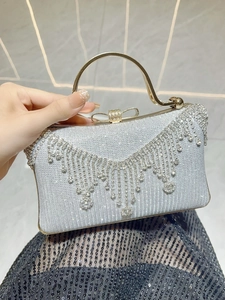 Close-up of silver evening clutch with sparkling rhinestone fringe and golden bow clasp