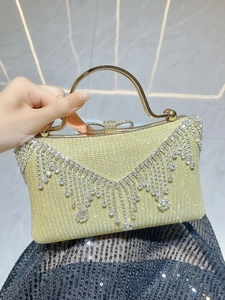 Detail of evening clutch featuring crystal tassels and a rhinestone bow clasp handle