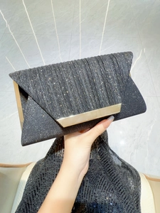 Detail of black pleated evening clutch bag with sparkling sequins and gold metal trim
