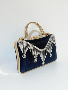 Detailed close-up of luxurious black evening clutch with rhinestone tassels and gold frame