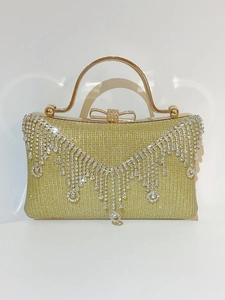Detail of champagne evening clutch with sparkling rhinestone tassels and bow clasp