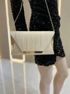 Detail of elegant gold glitter evening clutch with a thin metal chain and vertical textures