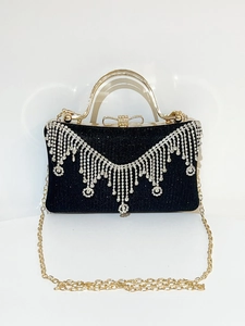 Close-up of black evening clutch with sparkling rhinestone fringe and gold top handle