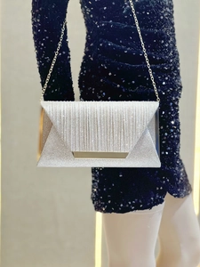 Silver clutch bag with vertical texture and gold metal trim on elegant evening dress