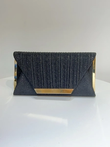 Detail of elegant black envelope evening clutch with glitter fabric and gold metallic edges