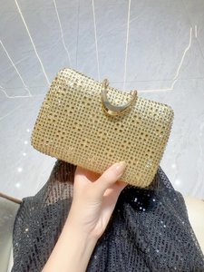 Detail of elegant gold rhinestone evening clutch with curved handle held by a model
