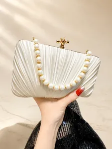 Detail of pleated satin evening bag with pearl and rhinestone handle in champagne gold