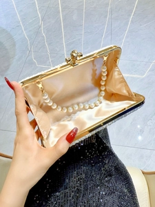 Elegant pleated evening clutch with pearl decorations and golden metal frame held by hand