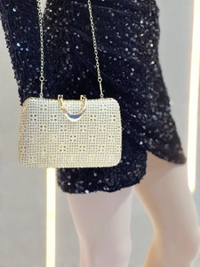 Detail of champagne gold rhinestone clutch bag with elegant metal handle and chain