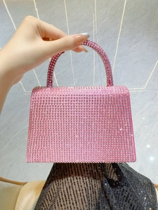 Detail of pink rhinestone handbag with shimmering crystals held against a dark outfit