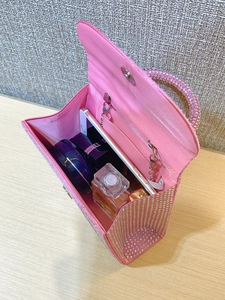 Internal storage of pink satin evening bag showing space for phone and perfume