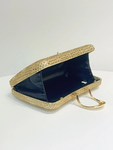 Detailed shot of gold evening clutch bag with champagne rhinestones and metal ring handle