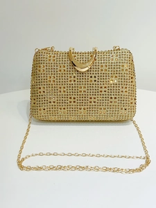 Close-up of luxury gold evening clutch with rhinestones, metal handle and chain strap