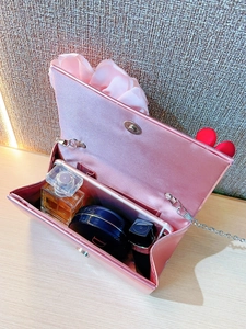 Pink satin evening bag interior capacity showing perfume, lipstick, and smartphone
