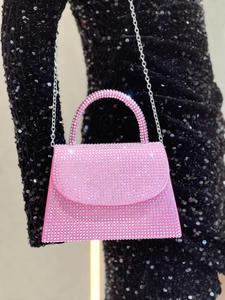 Detail of pink rhinestone evening bag with silver chain strap on a black sequin dress