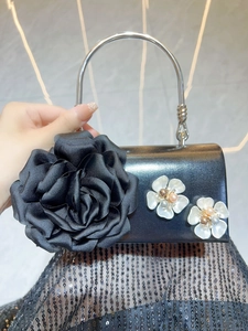Detail of black evening clutch with large 3D rose flower and silver metal handle