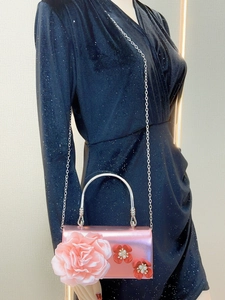 Pink evening clutch bag with large fabric flowers on black sequined evening dress