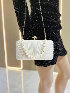 Detail of pleated silk evening clutch with pearl handle and golden metal clasp