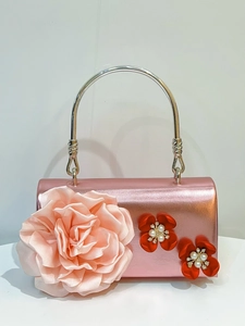 Close-up of pink satin evening bag with a large 3D rose flower and pearl center