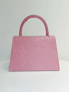 Detailed close-up of shiny pink rhinestone covered square handbag with a crystal handle