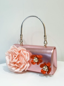 Close-up of pink metallic party handbag with 3D fabric flowers and pearl accents