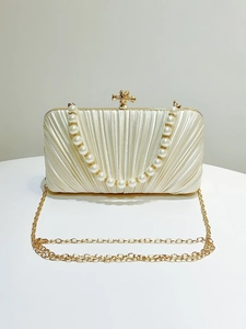 Close-up of pleated evening clutch with pearl handle and golden clasp hardware