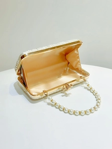 Detail of white pleated evening bag with pearl handle and apricot satin lining