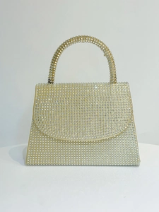 Macro detail of champagne gold evening bag encrusted with sparkling rhinestones