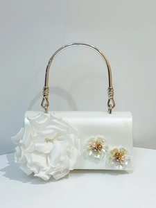 Detail of white satin evening bag with floral design and round silver metal handle