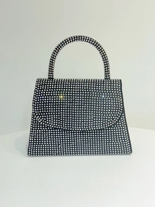 Detail of a trapezoidal black evening bag covered in sparkling silver rhinestones