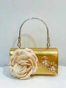Detailed view of elegant gold evening clutch featuring a large 3D satin rose and pearls