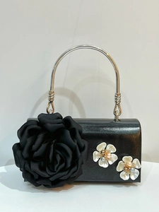 Detail of elegant black floral evening bag featuring 3D rose and pearl flower accents