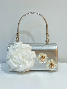 Detailed view of silver evening bag with 3D white satin flower and pearl accents