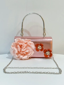Close-up of pink satin evening bag with decorative 3D fabric roses and silver chain