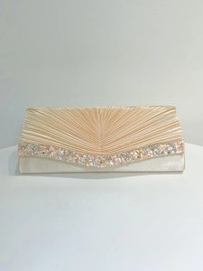 Détail de la pochette de soirée en satin champagne avec plis et bord en cristal