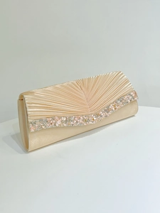 Détail d'une pochette de soirée élégante en satin champagne plissé avec bordure bijoux