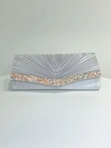 Détail d'une pochette de soirée en satin argenté avec rabat plissé et bordure rose