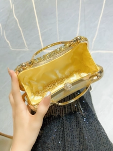 Luxurious gold evening clutch bag with rhinestones and chain strap held by a hand
