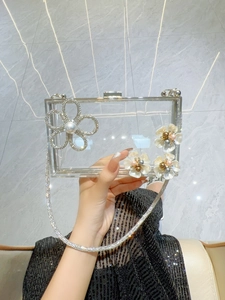 Detail of transparent acrylic clutch with rhinestone flower and pearls for evening gala