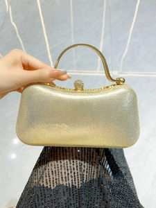 Close-up of golden evening clutch bag featuring a diamond-encrusted sphere clasp and handle