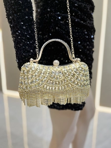 Detail of gold evening clutch with sparkling rhinestones, metal handle, and tassel fringe
