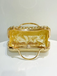 Detail view of open gold evening clutch with crystal edges and metal chain strap