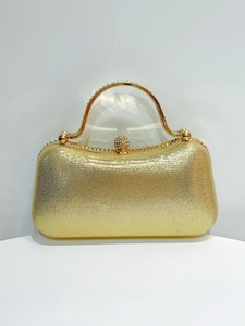 Detailed view of sparkly gold evening clutch with rhinestone handle and spherical clasp