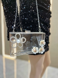 Close-up of transparent acrylic clutch bag with pearl flowers and rhinestone decorations