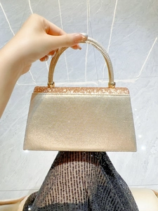 Detail of champagne gold glitter evening bag featuring a metallic handle and sequin texture
