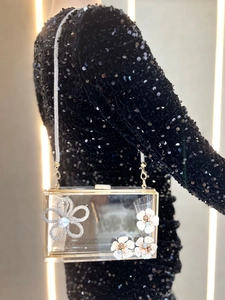 Detailed close-up of a clear acrylic evening bag with crystal flowers and gold metal edges