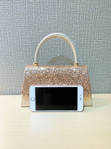 Rose gold sequined evening bag with metal handle and smartphone for size reference