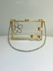 Detail of acrylic evening clutch featuring rhinestone flowers and gold metal frame
